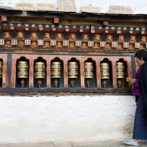 Bhutanese woman turning Buddhist prayer wheels, Trashi Chhoe Dzong, Thimphu, Bhutan, Asia