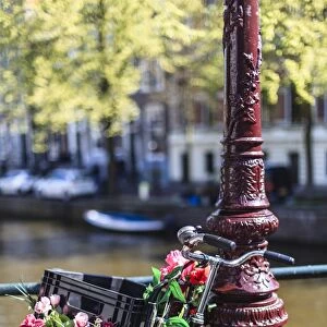 A bicycle decorated with flowers by a canal, Amsterdam, Netherlands, Europe