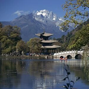 Black Dragon Pool park with bridge and pagoda, and mountains in the background at Lijiang