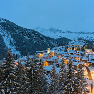 Blue dusk over snowcapped mountains and woods around the alpine huts of Pianazzo