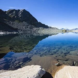 Blue sky and rocky peaks reflected in the blue Lago Nero, Chiavenna Valley, Valtellina