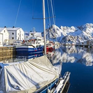 Boats docked in the calm waters of the port of Henningsvaer with the reflection of fishermens houses and Norwegian Alps, Lofoten Islands, Arctic, Norway, Scandinavia, Europe