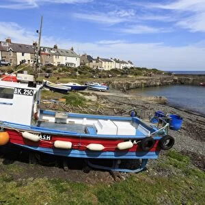 Boats on harbour foreshore at low tide on a sunny summer day, Craster, Northumberland
