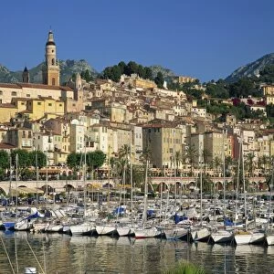 Boats in the harbour with the houses and church of the town of Menton behind