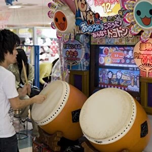 Boy playing a Japanese taiko drum video game at a game center, Japan, Asia