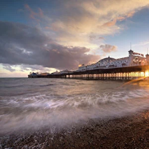 Brighton Pier at sunset with dramatic sky and waves washing up the beach, Brighton