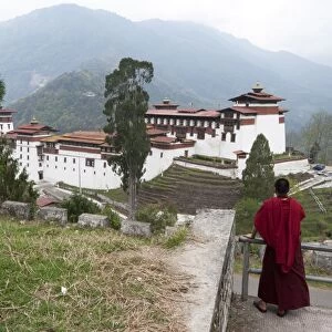Buddhist monk looking back at Trongsa Dzong, Bhutans largest monastery fortress