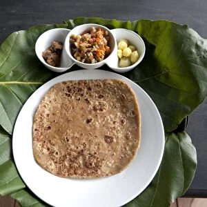 Burmese lunch of chapati with beef curry, vegetables and potatoes, served on teak leaf mat