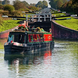 A canal boat leaving the famous series of locks at Caen Hill on the Kennet and Avon Canal, Wiltshire, England, United Kingdom, Europe