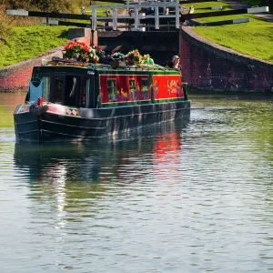 A canal boat leaving the famous series of locks at Caen Hill on the Kennet and Avon Canal, Wiltshire, England, United Kingdom, Europe