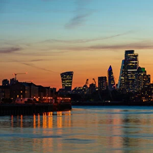 The City of London skyline at sunset reflecting in River Thames, London, England, United Kingdom, Europe