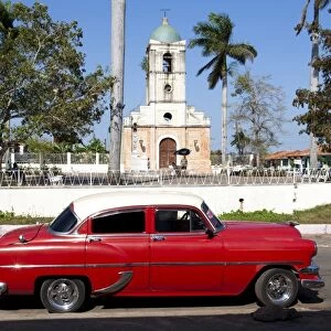 Classic red American car parked by the old square in Vinales village, Pinar del Rio