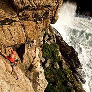 A climber on the classic extreme route Raven Wall on the cliffs at Bosigran, near St