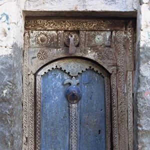 Close-up of a blue door in a carved wood frame in the