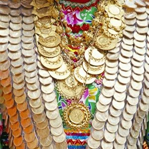 Close-up of a girls dress decorated with old gold coins