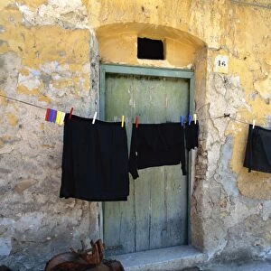Clothes on a washing line outside an old house with