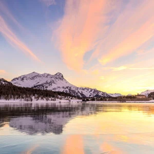 Colors of sunset reflected on the icy surface of Lake Sils, Engadine Valley, Graubunden