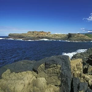 Columnar structures, created during cooling of basalt lava, with an intrusion or dyke of darker rock in the foreground, near Bombo Beach, Kiama, south coast, New South Wales