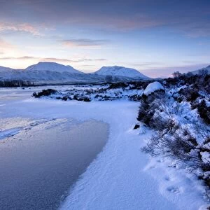 Dawn view of frozen Loch Ba on snow-covered Rannoch Moor, Highland, Scotland