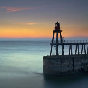 Daybreak over Whitby East Pier and lighthouse, North Yorkshire, England, United Kingdom