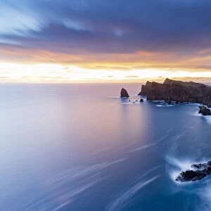Dramatic sky at dawn on cliffs washed by ocean from Ponta Do Rosto viewpoint