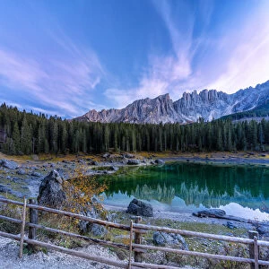 Dramatic sky at sunset over Carezza Lake and Latemar peaks in autumn, Dolomites