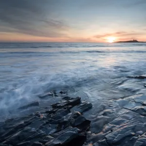 Dunstanburgh Castle at sunrise, seen from Embleton Bay, Northumberland, England, United Kingdom