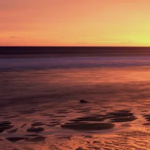 Dunstanburgh castle at sunrise, view across Embleton Bay, Northumberland