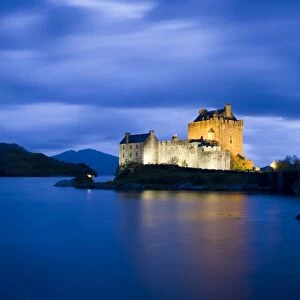 Eilean Donan Castle floodlit against the deep blue twilight sky and water of Loch Duich