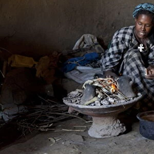 Ethiopian woman setting fire to boil the water for coffee for traditional ceremony