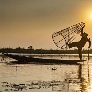 Fisherman at Inle Lake with traditional Intha conical net at sunset, fishing net
