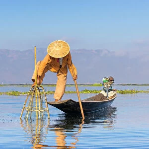 Fisherman with traditional conical net on boat, Lake Inle, Shan State, Myanmar (Burma), Asia