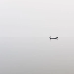 A fishing boat on a perfectly calm Indawgyi Lake in northern Myanmar on a misty afternoon