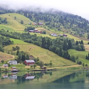 Fjordside houses and wooded hills with low cloud, Nordfjord, Olden, Norway, Scandinavia, Europe
