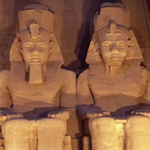 Floodlit colossi of Ramses II (Ramesses the Great), seated statues on facade of temple