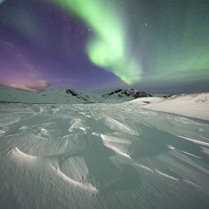 Frozen snow lit by green lights of the Northern Lights (Aurora Borealis