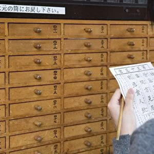 A girl reads her omikuji (paper oracle) at Sensoji Temple in Asakusa, Tokyo, Japan, Asia