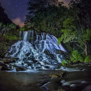 A glowing waterfall at night with the Milky Way above, Kapaa, Hawaii