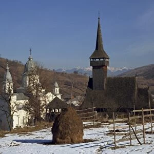 Haystack in snow covered field with two churches in the background at Botita village