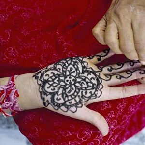 Henna designs being applied to a womans hand