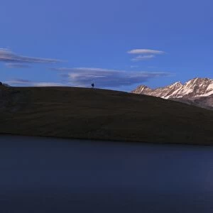 Hiker admires sunset on Rossett Lake at an altitude of 2709 meters, Gran Paradiso National Park