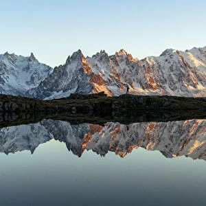 Hiker admiring Dent du Geant and Mont Blanc covered with snow reflected in Lacs des
