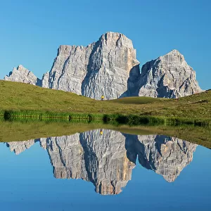Hiker and Mount Pelmo reflected in the water of Baste Lake on a sunny day, Belluno Dolomites, Belluno province, Veneto, Italy, Europe