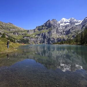 Hikers admire Lake Oeschinensee, Bernese Oberland, Kandersteg, Canton of Bern, Switzerland