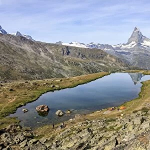 Hikers admire the Matterhorn reflected in Lake Stellisee, Zermatt, Canton of Valais