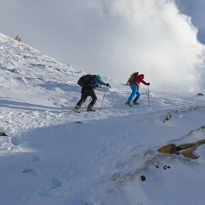Hikers proceed in the snowy valley of Alpe Fora, Malenco Valley, Province of Sondrio