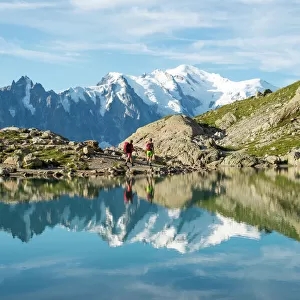Hikers and the summit of Mont Blanc reflected in Lac Blanc on the Tour du Mont Blanc