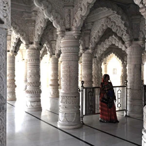 Hindu woman in red sari inside the ornate white marble Swaminarayan Temple, built