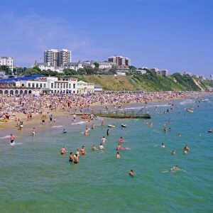 Holidaymakers in the sea and on the beach, Bournemouth, Dorset, England, UK