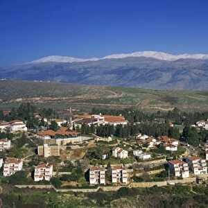 Houses and stadium in town of Metula in Upper Galilee, with snow covered Mount Hermon in background